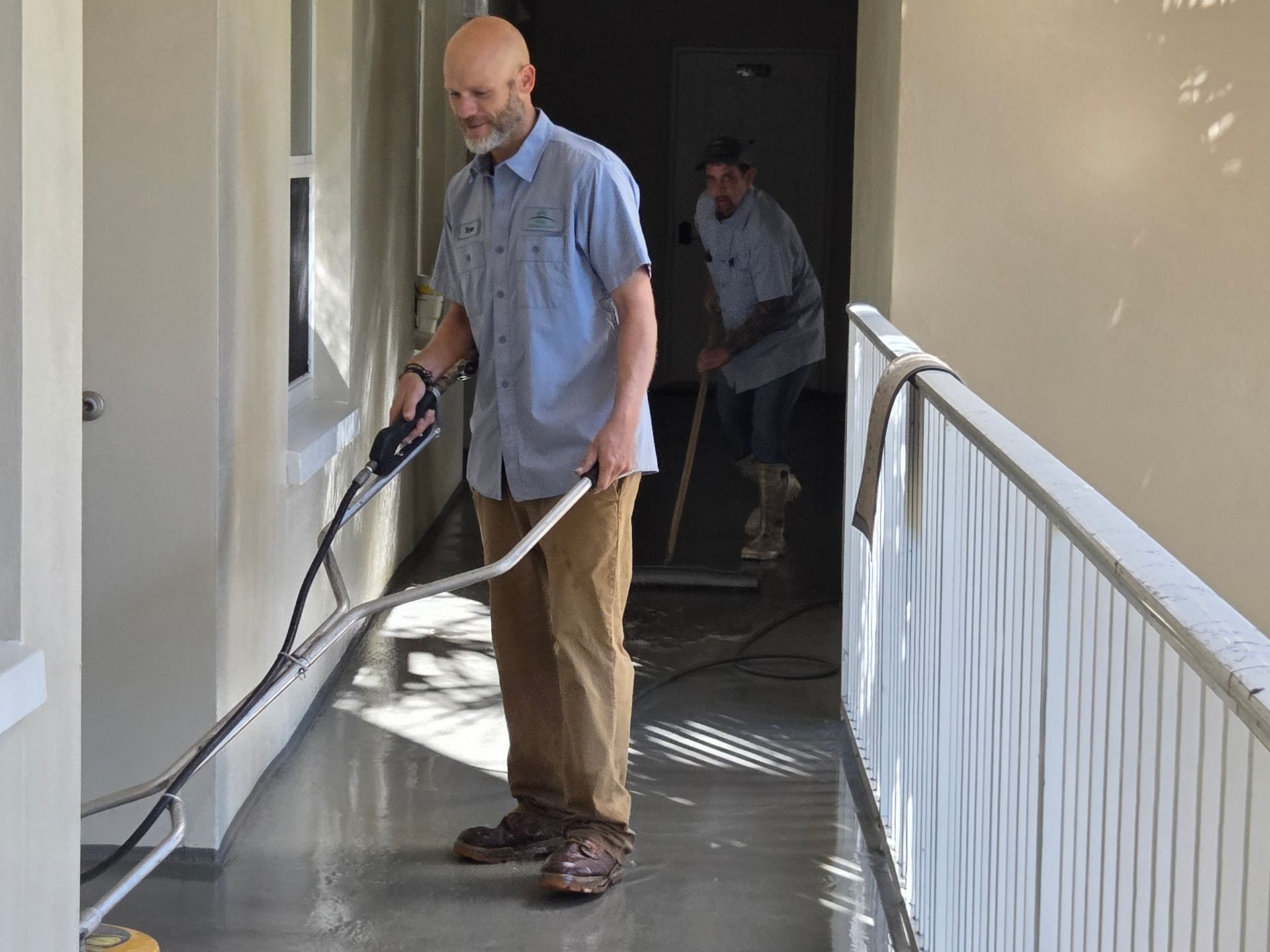 A man wearing a hard hat and an orange vest is standing with his arms crossed.