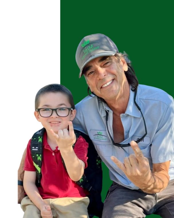 A man wearing a hard hat is looking at his cell phone.