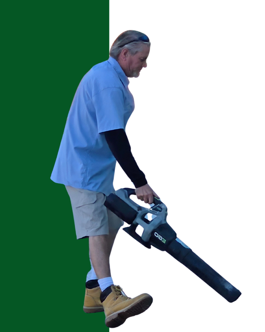 A man in green overalls is mopping the floor next to a caution wet floor sign.