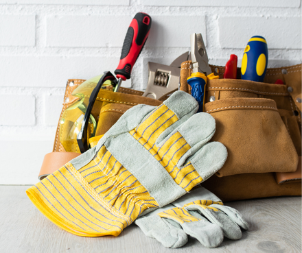 A man wearing a hard hat is holding a multimeter and smiling.
