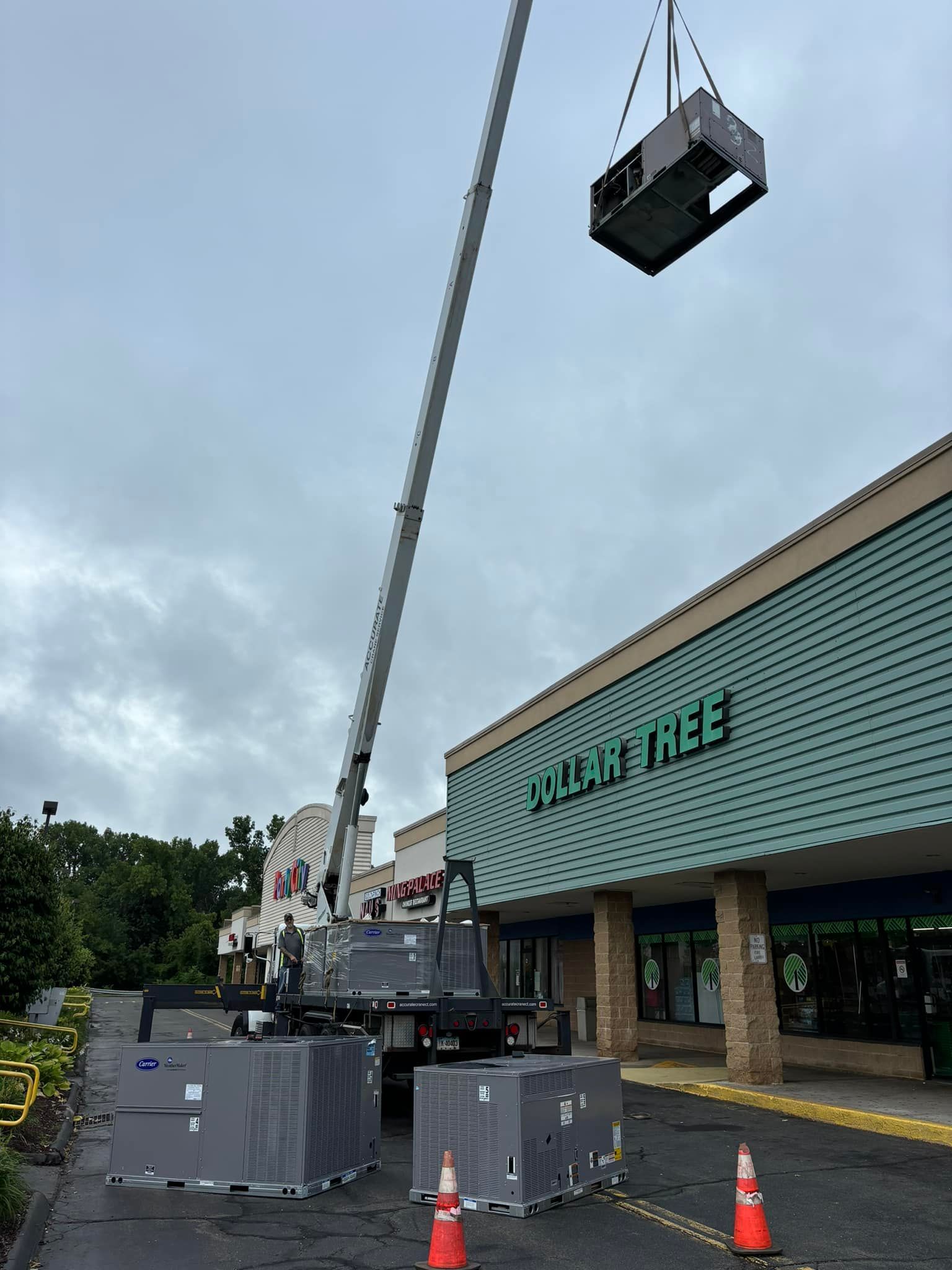 A crane is lifting a machine in front of a store called acorn tree