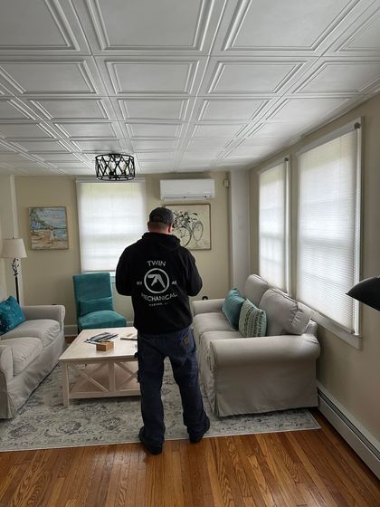 A man is standing in a living room looking at the ceiling.