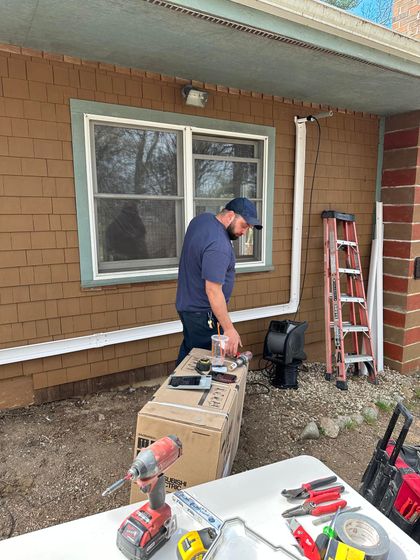 A man is working on a window on the side of a house.