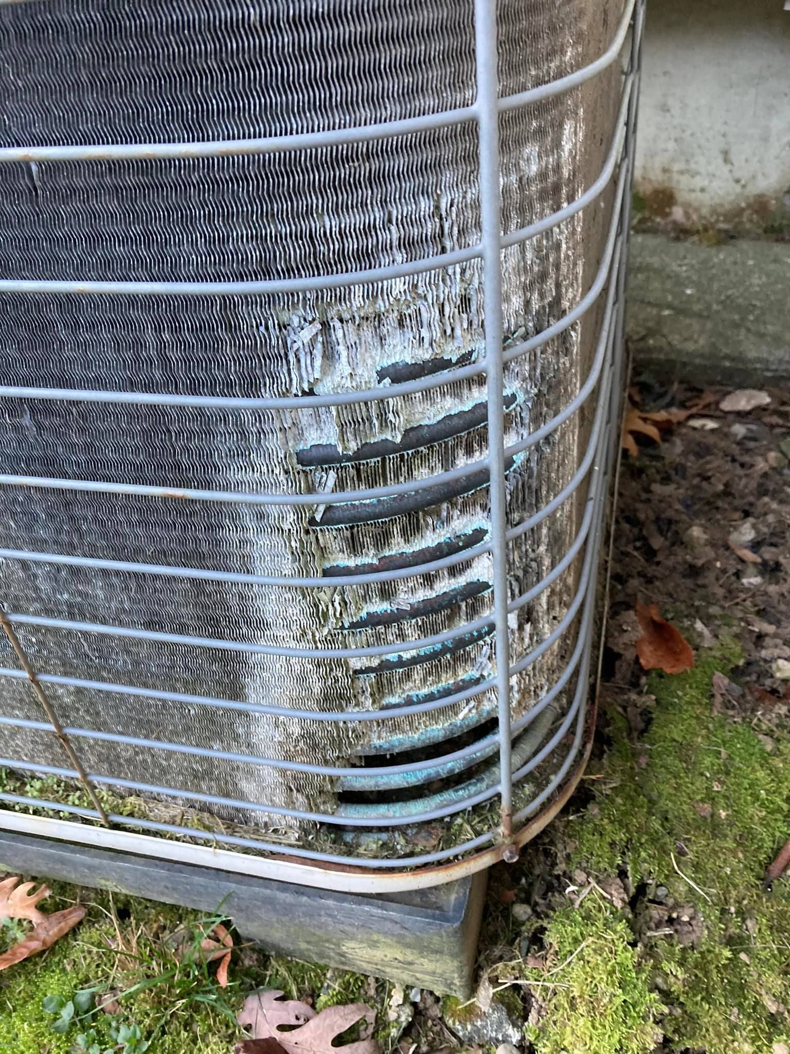 A close up of a dirty air conditioner sitting on the ground.