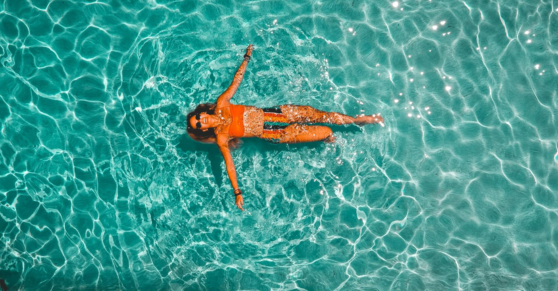 An aerial view of a woman floating on her back in a swimming pool.