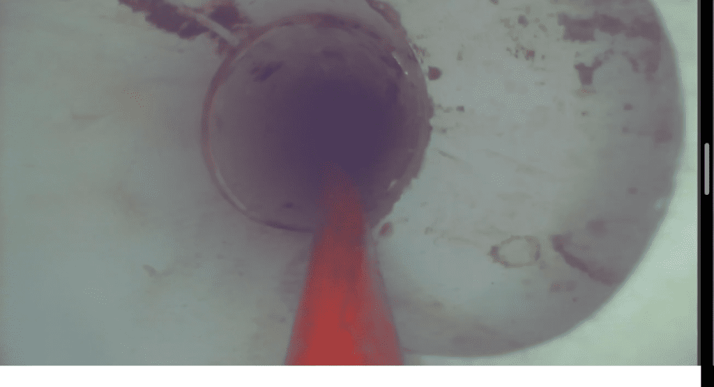 A red cone is coming out of a hole in a pipe.