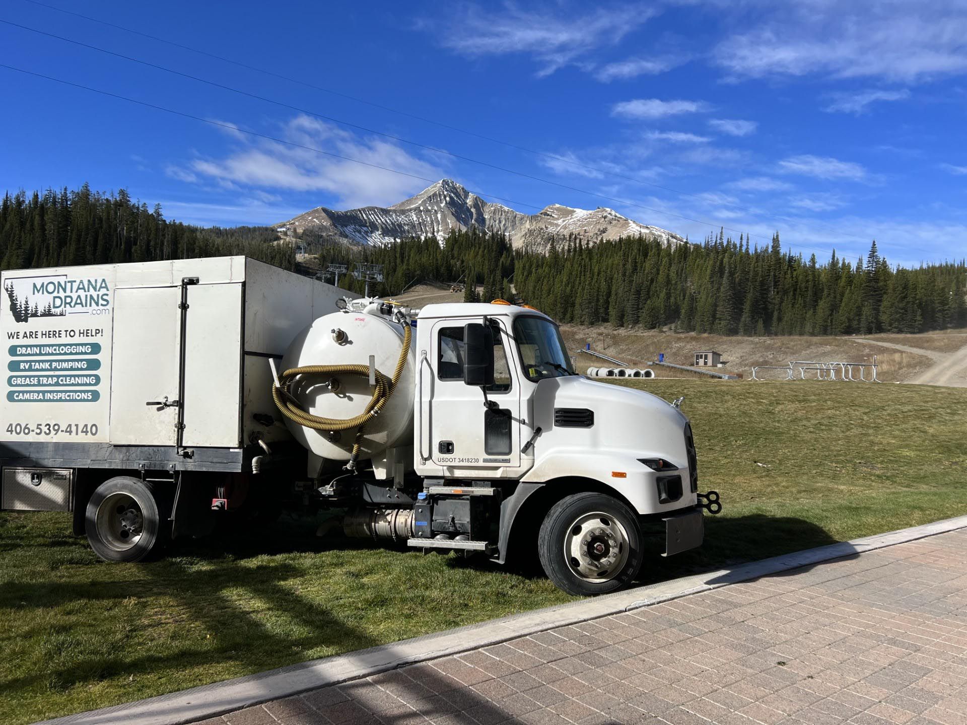 A white vacuum truck is parked on the side of the road.
