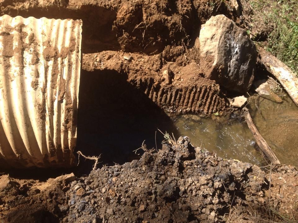 A pipe is laying in the dirt next to a rock