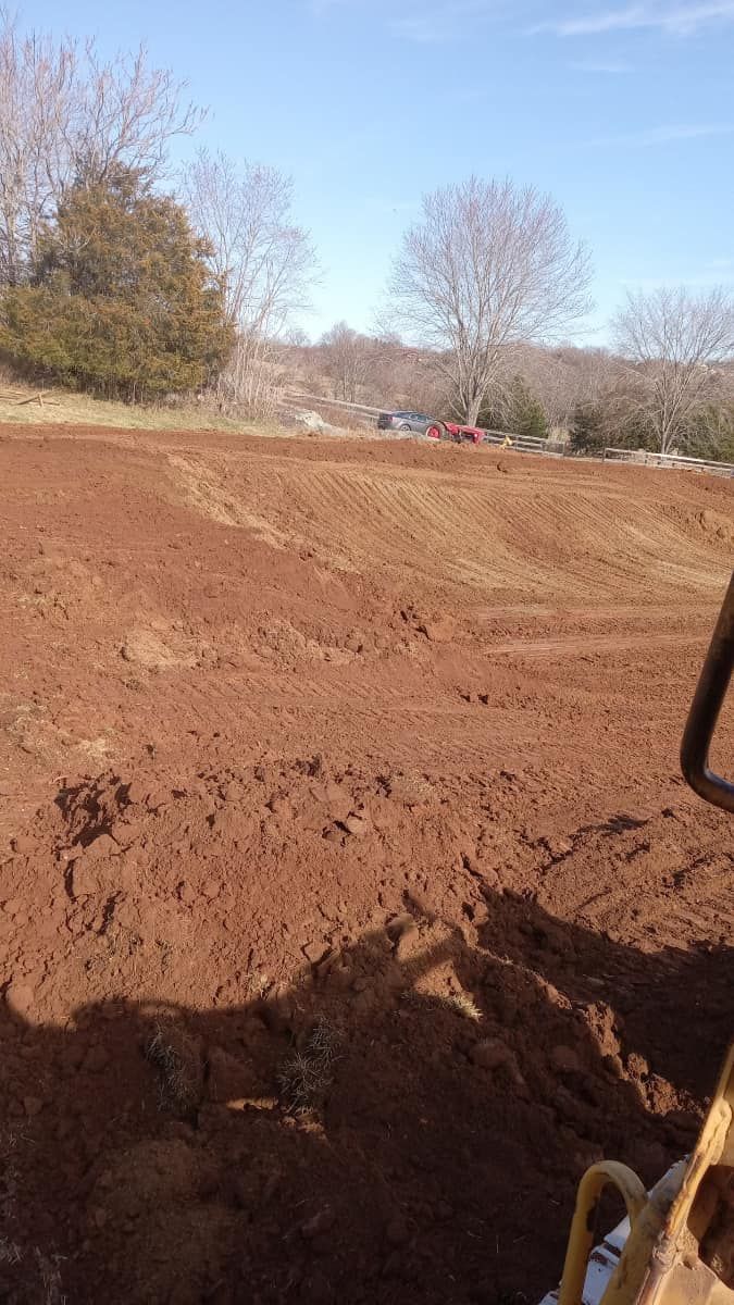 A person is driving a bulldozer through a dirt field.