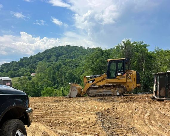 A bulldozer is sitting in a dirt field next to a truck.