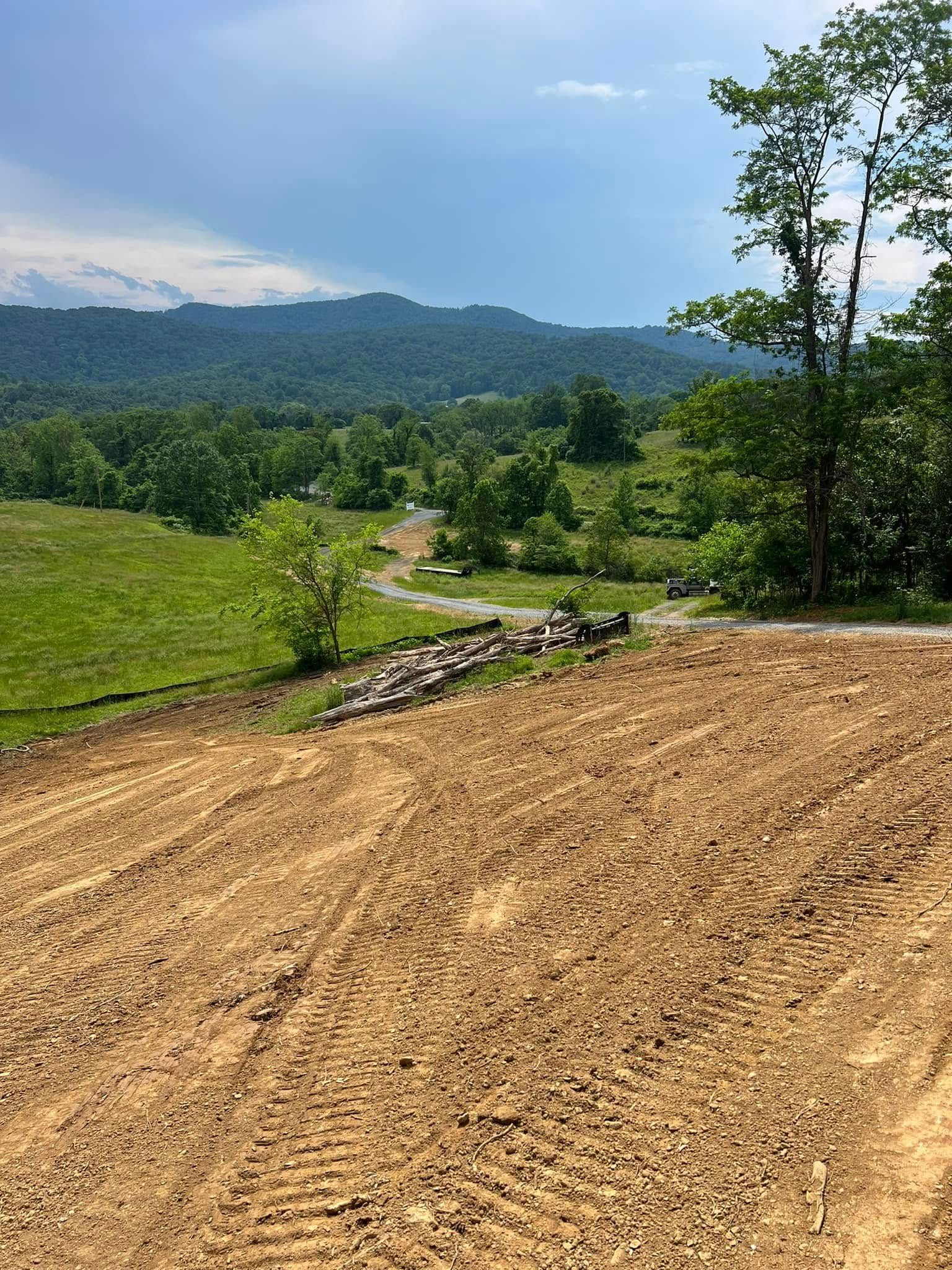 A dirt field with trees and mountains in the background.