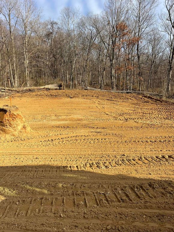 A large dirt field with trees in the background.