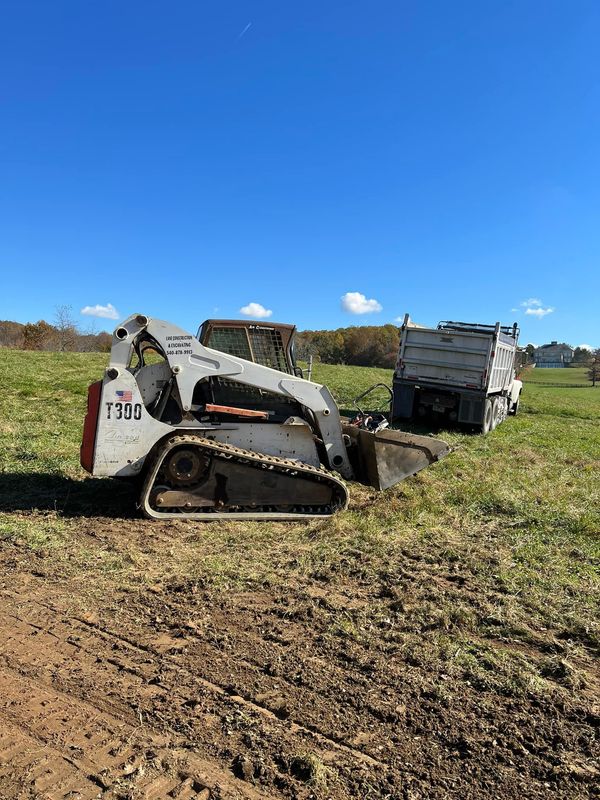 A bulldozer is sitting in the middle of a field next to a dump truck.