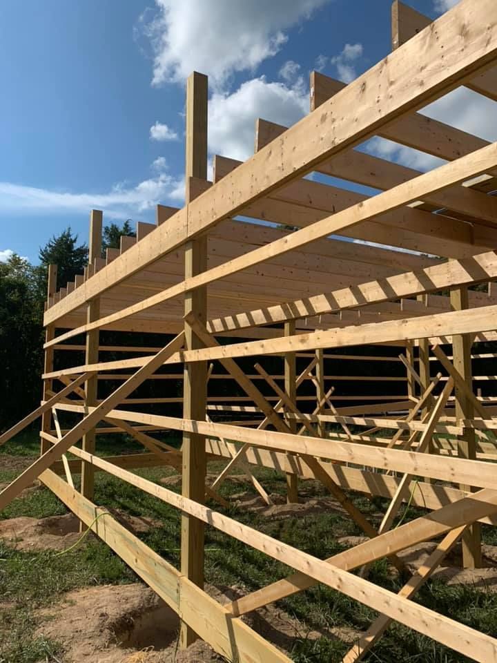 A large wooden structure is being built in a field.