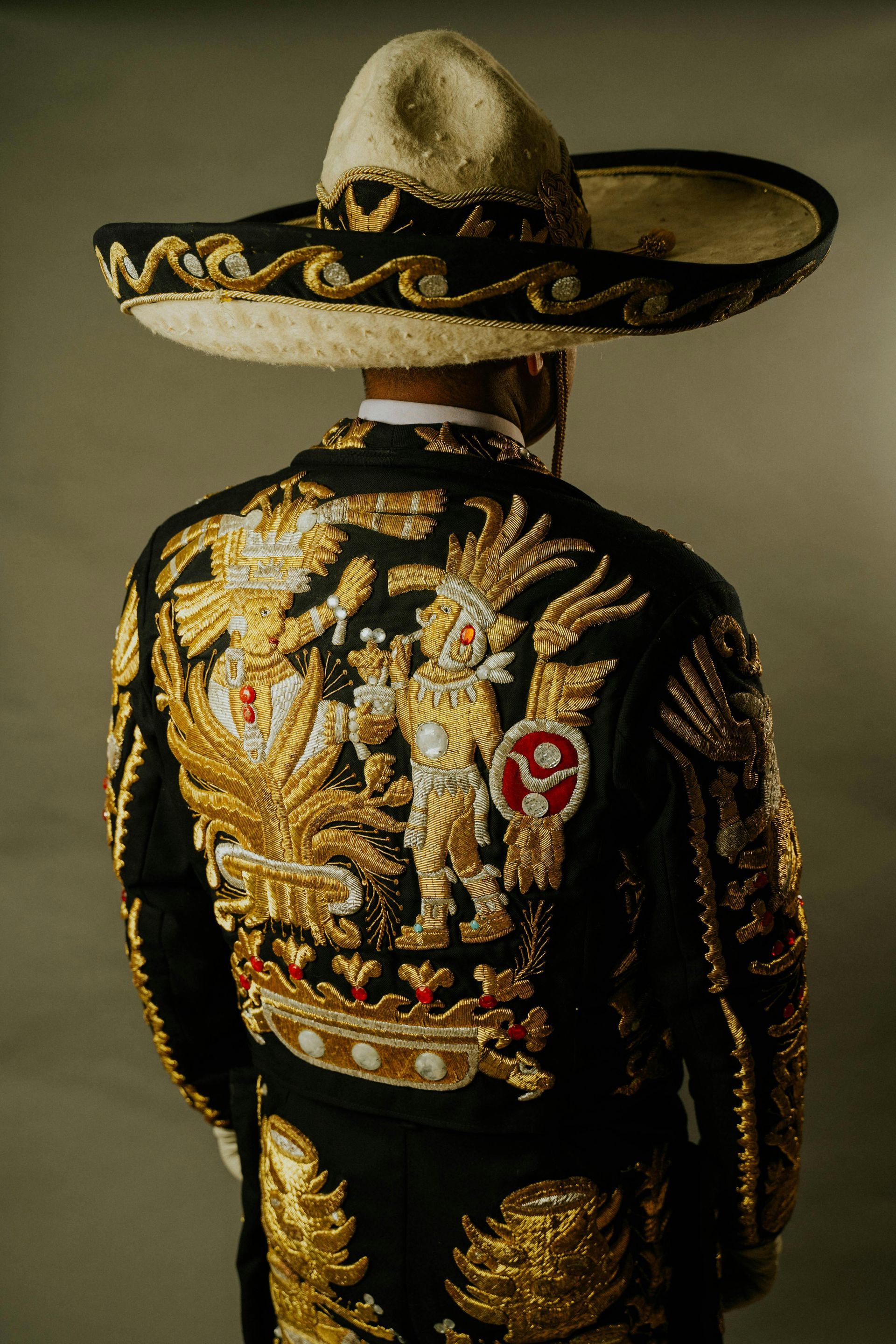 Un hombre lleva un sombrero y un traje negro y dorado.
