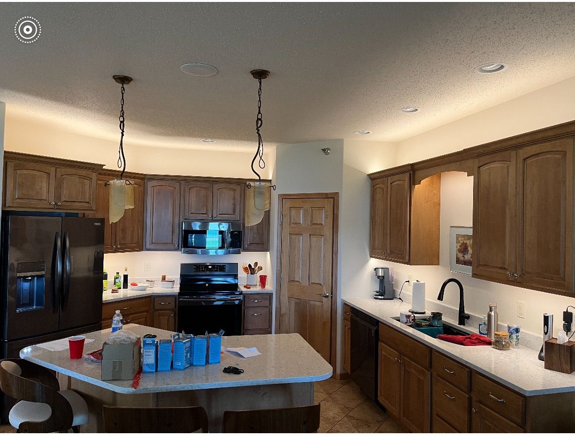 A kitchen with wooden cabinets , a refrigerator , a sink , and a stove.