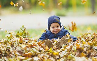 A little boy is laying in a pile of leaves.