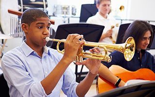 A young man is playing a trumpet in a band.