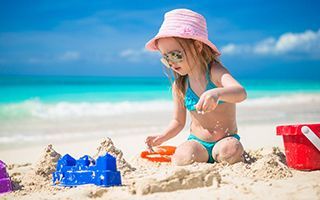 A little girl is playing in the sand on the beach.