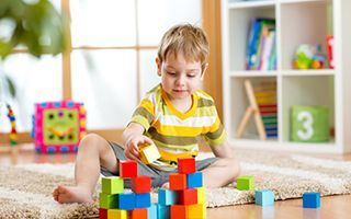 A young boy is sitting on the floor playing with blocks.