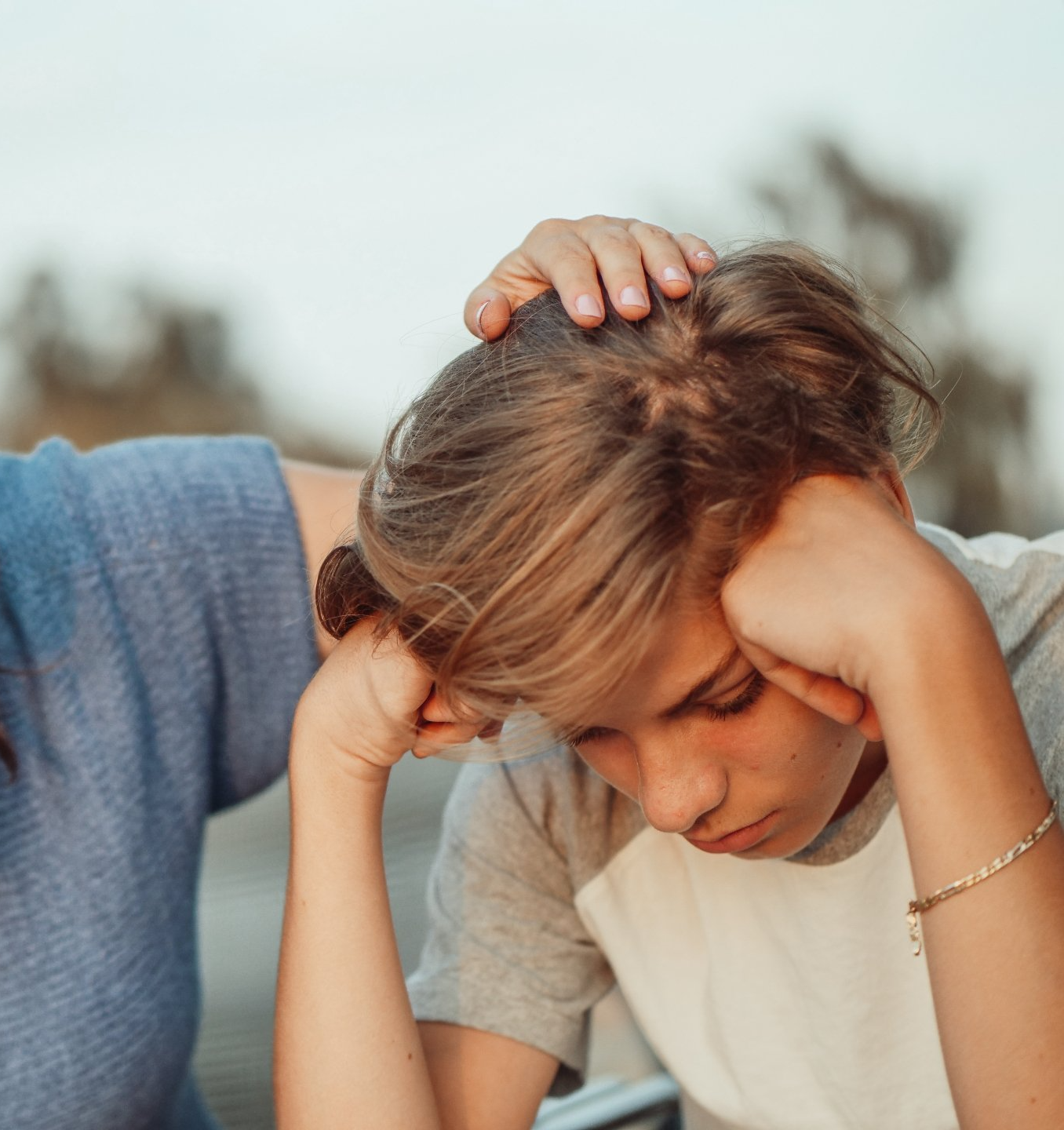 Sad, disappointed teen being comforted by someone rubbing his head