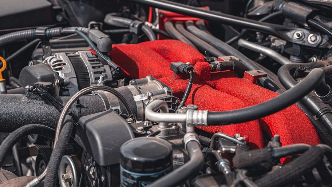 Close-up of a car engine with various black and silver parts, including a red cloth.