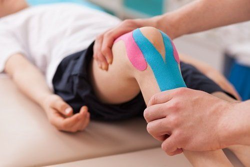 Fisioterapista azionando il ginocchio di un bambino