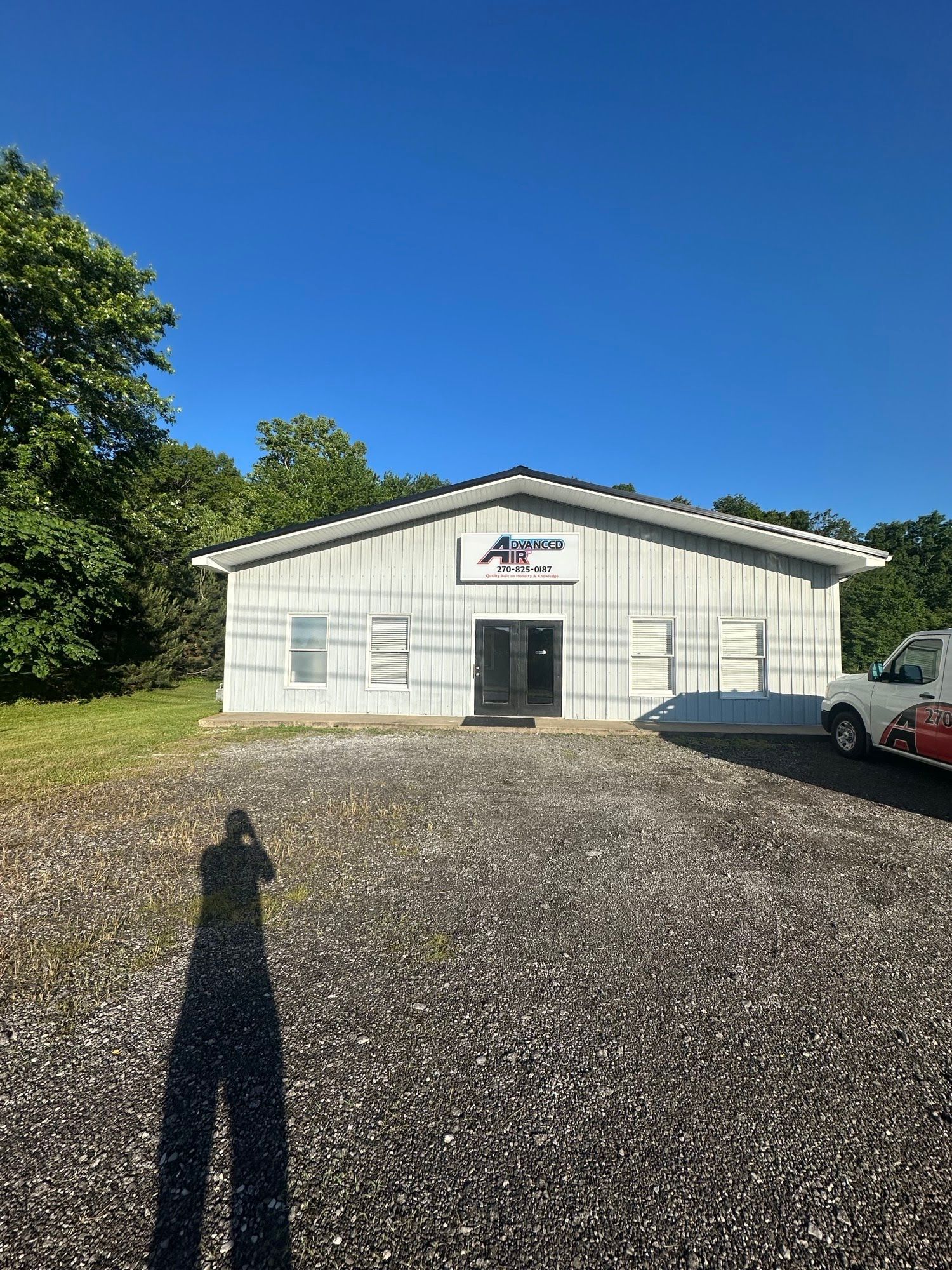 A white building with a red van parked in front of it.