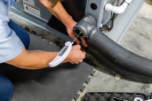 A man is using a thermometer to check the temperature of a pipe.