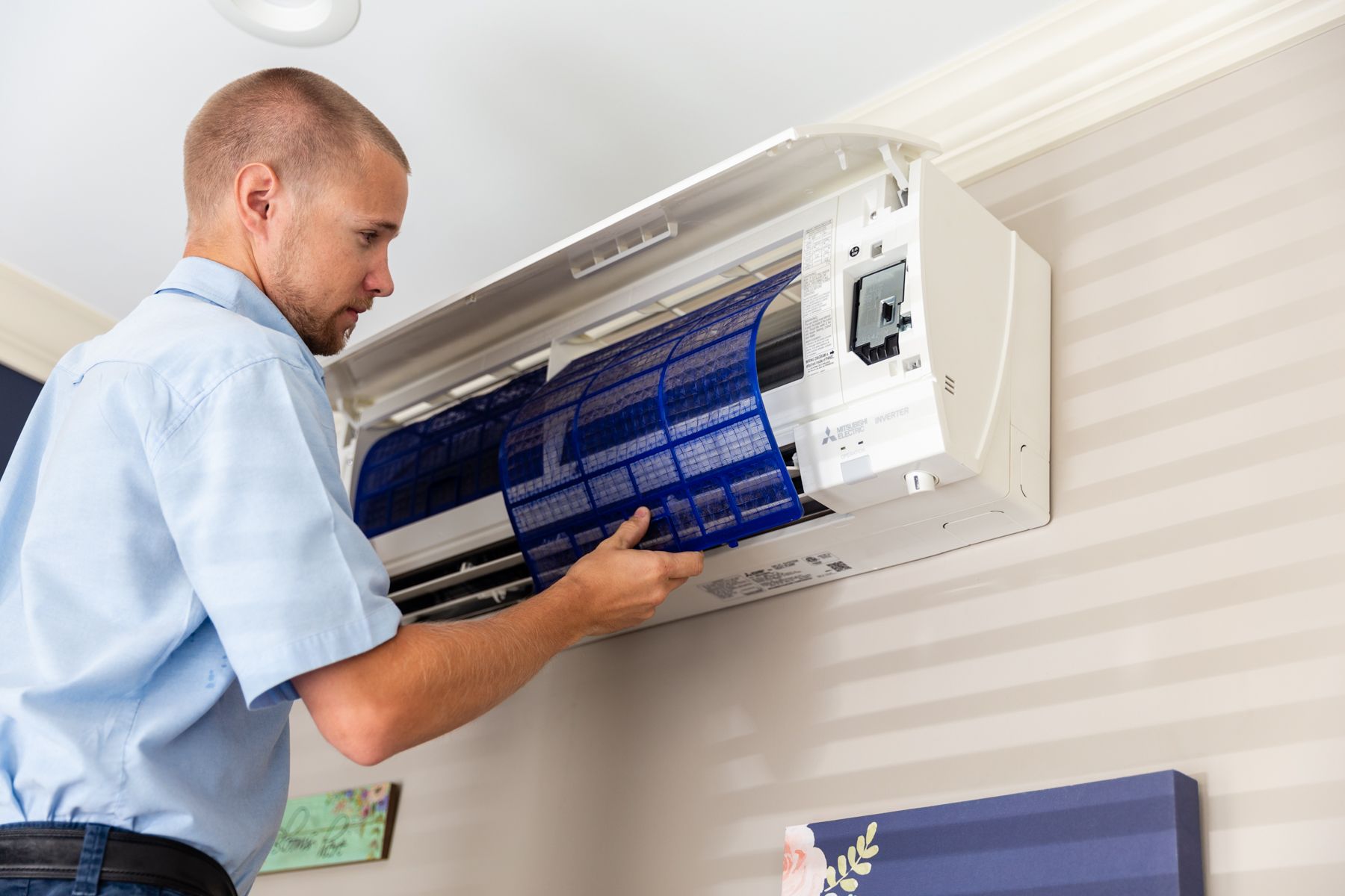A man is cleaning the filter of an air conditioner.