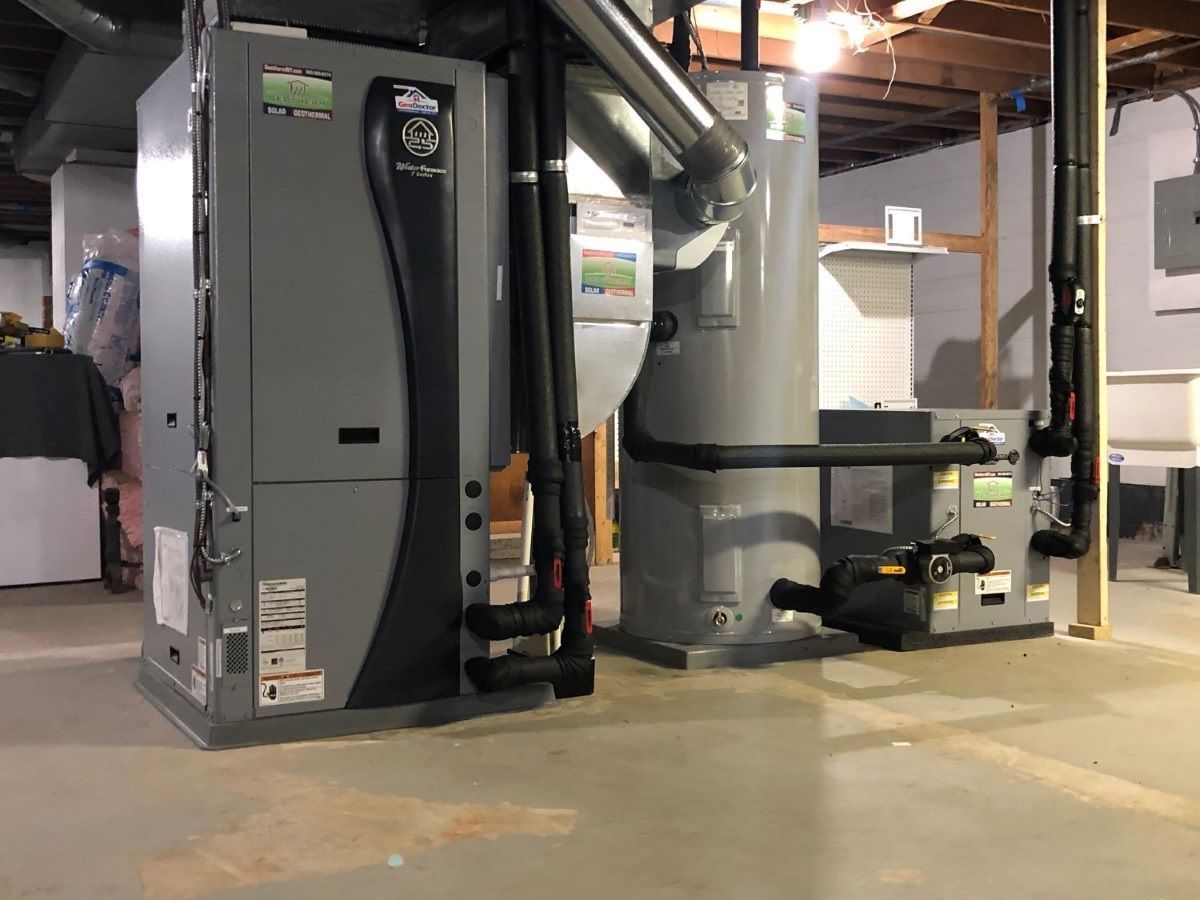 A boiler and a water heater are sitting in a basement.
