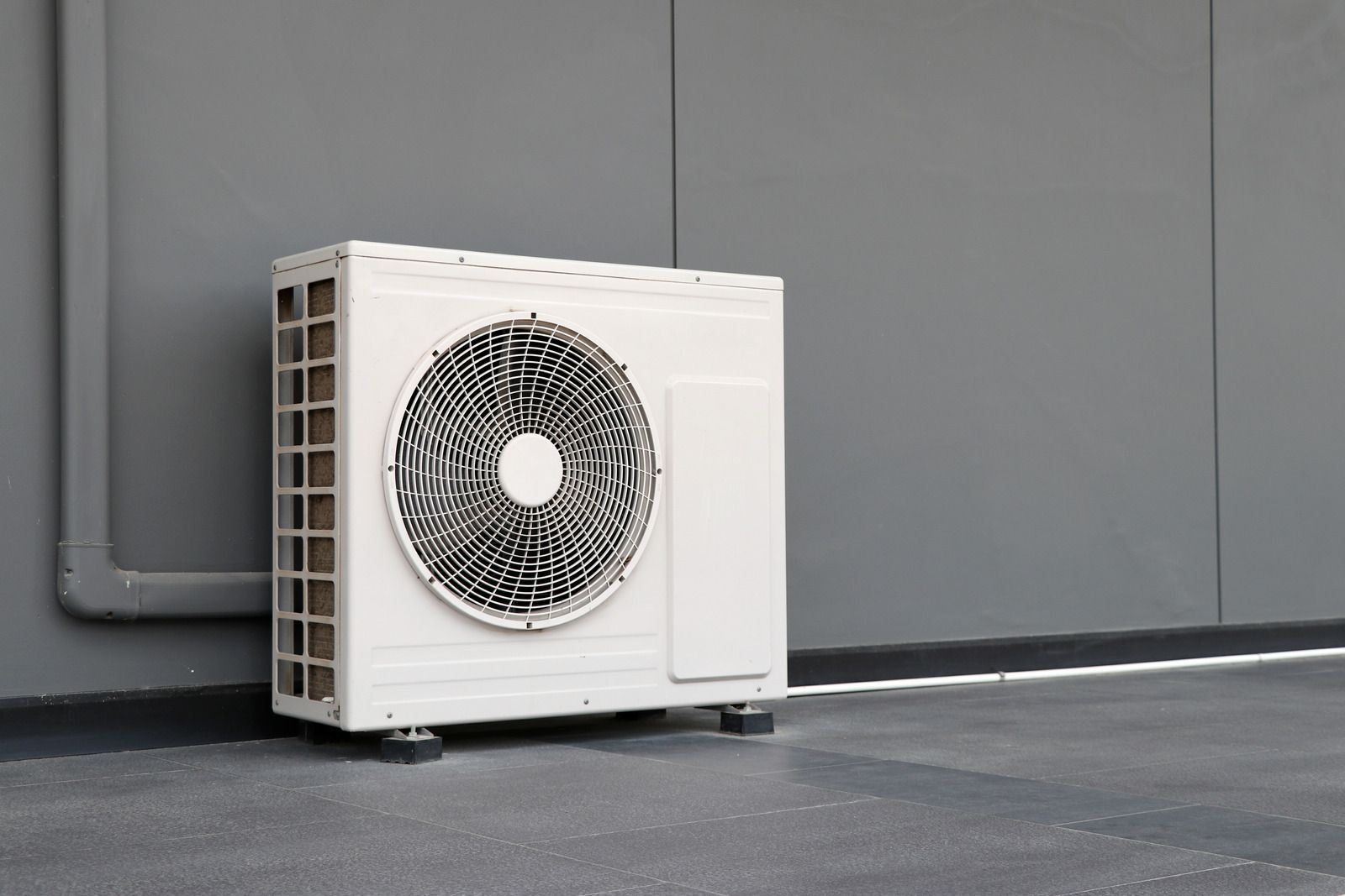 A white air conditioner is sitting on the side of a building.