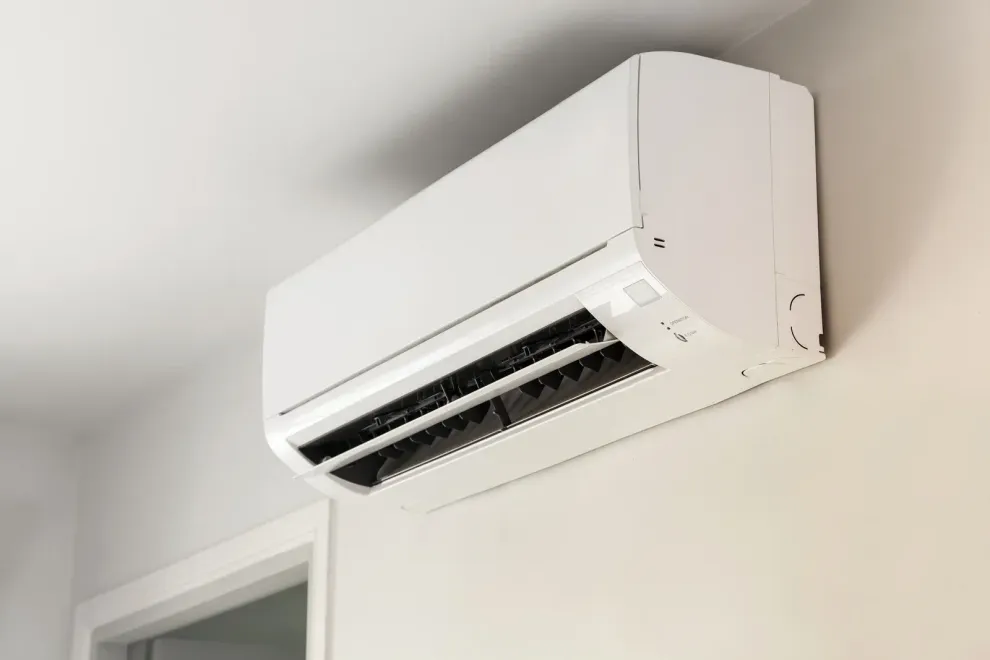 A white air conditioner is hanging from the ceiling in a room.