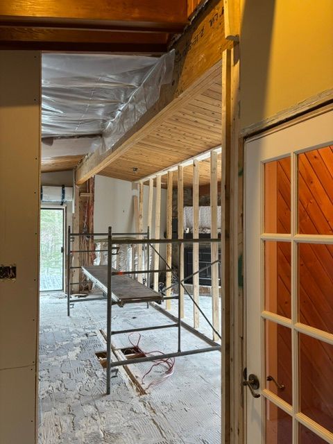 Intérieur d'un bâtiment en rénovation, montrant la charpente apparente, les échafaudages et une porte.