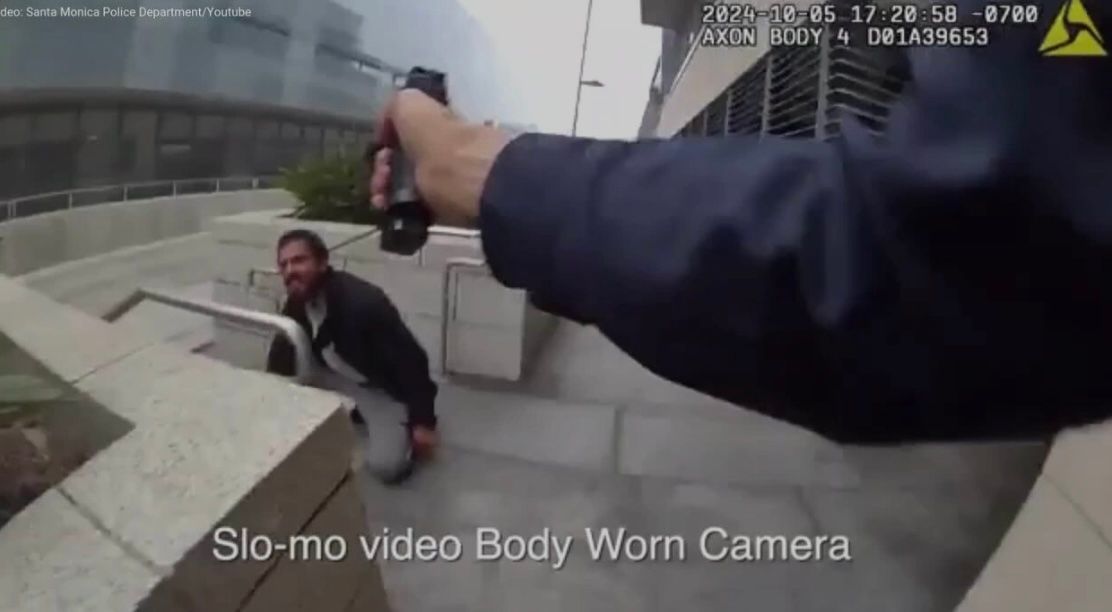 A person is holding a video body worn camera in front of a man.