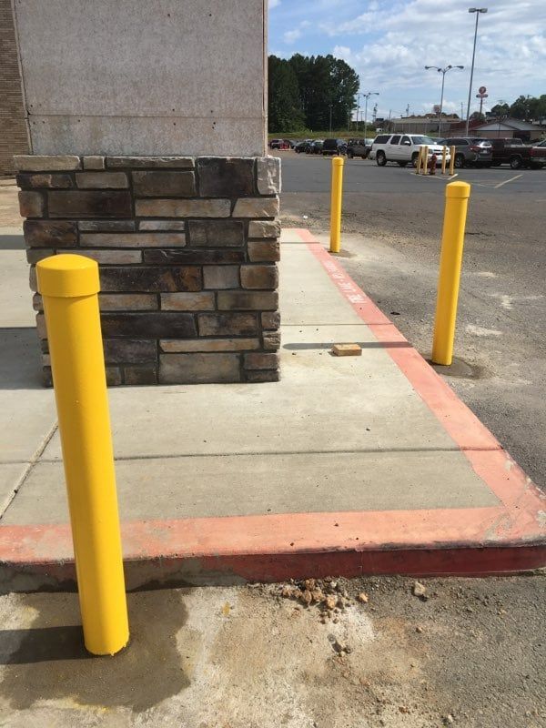 A sidewalk with yellow poles in front of a building