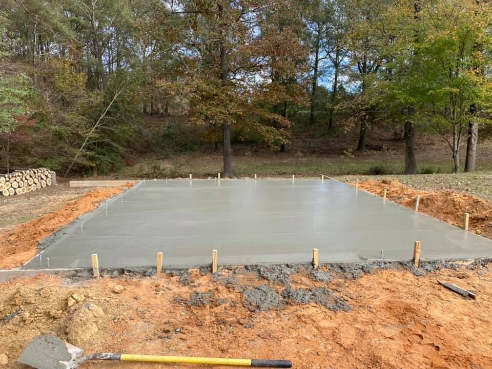 A shovel is sitting on top of a concrete slab in the dirt.