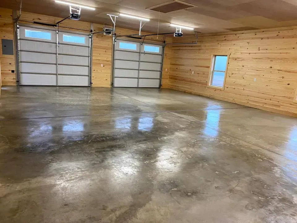 A large empty garage with two garage doors and a concrete floor.