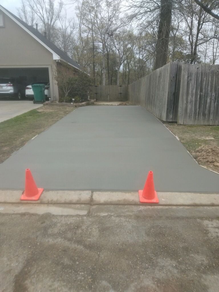 A concrete driveway with two orange cones on the side of it.