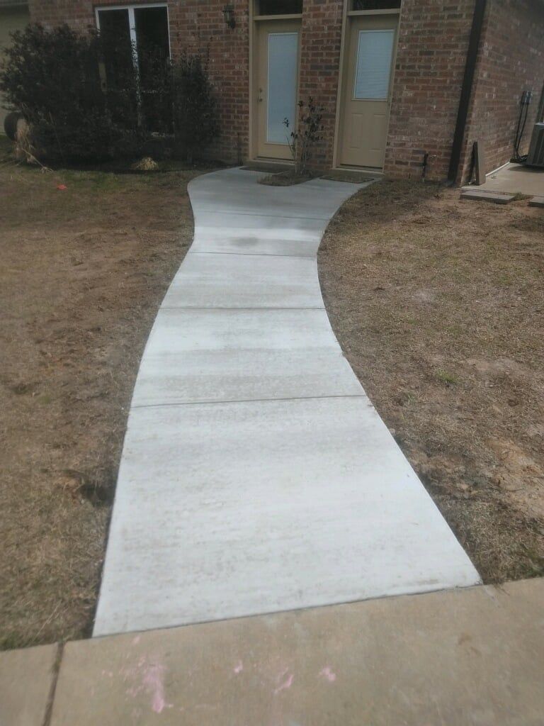 A concrete walkway leading to a brick house.