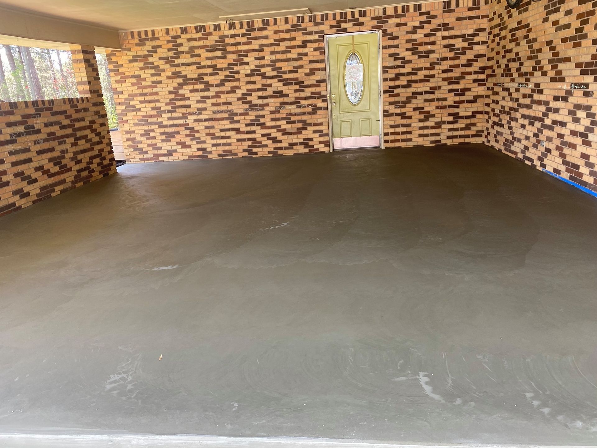 A garage with a brick wall and a concrete floor.