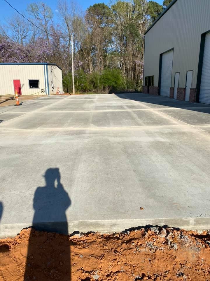A shadow of a person is cast on a concrete driveway in front of a building.
