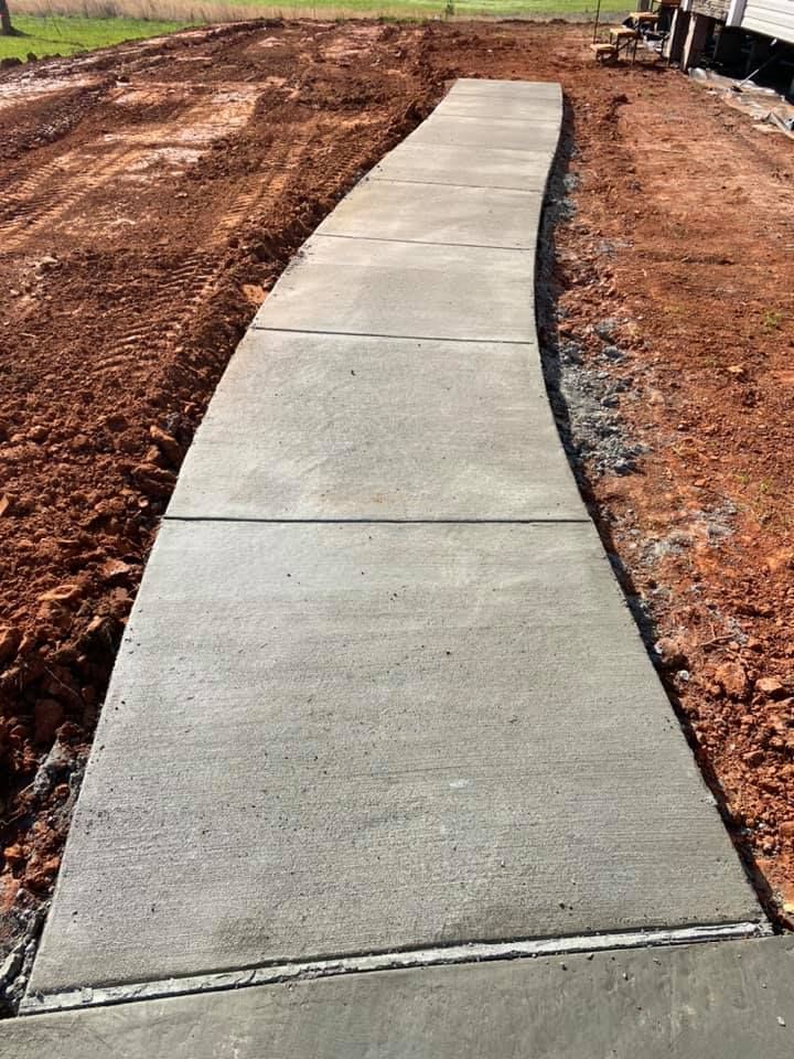 A concrete walkway is being built in a dirt field.
