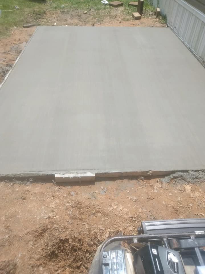A concrete floor is being built in a backyard next to a house.