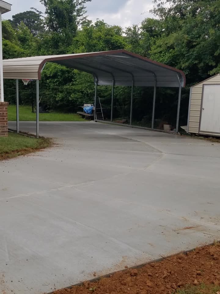 A carport in the middle of a driveway next to a house.