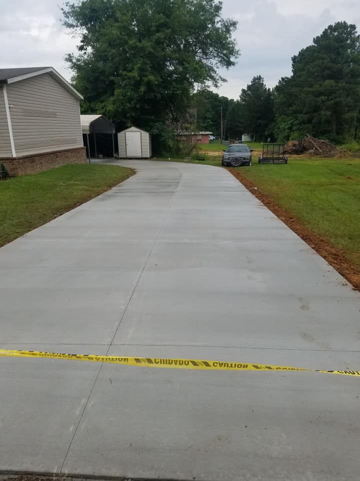 A concrete driveway leading to a house with a car parked on the side of it.