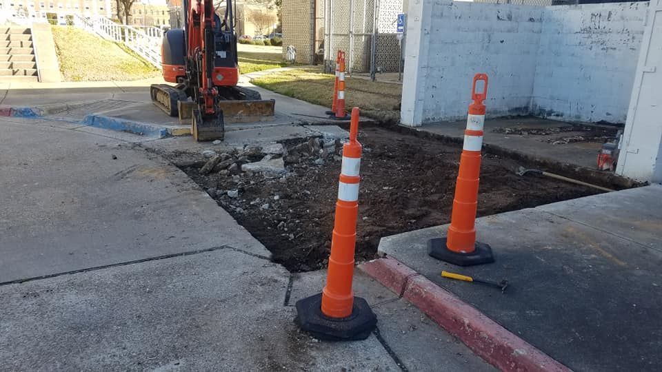 A construction site with orange cones and a small excavator.