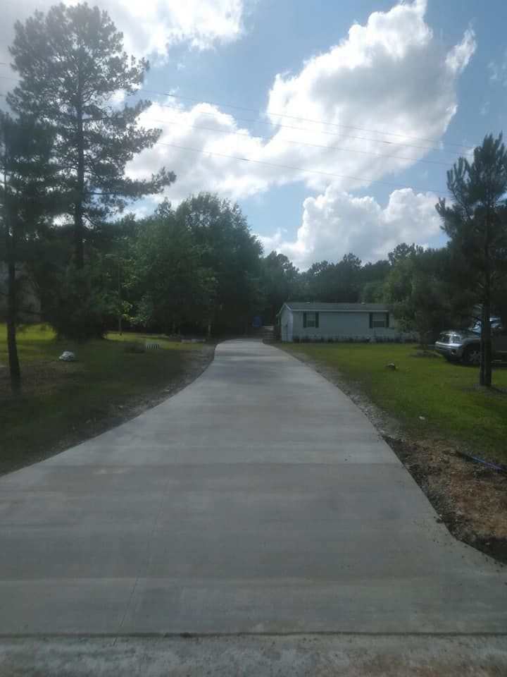 A concrete driveway leading to a house in the woods