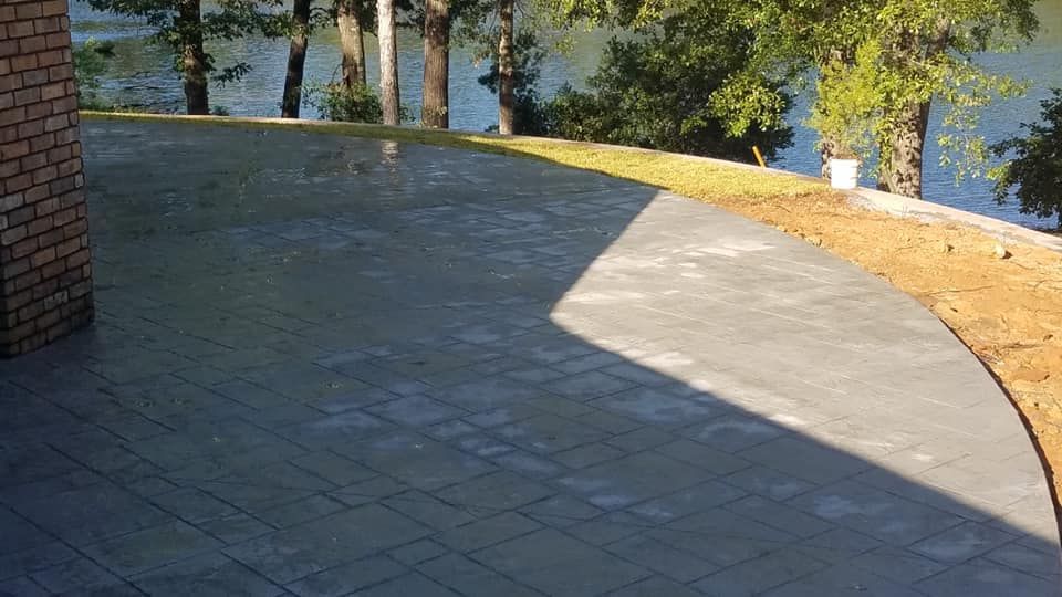 A concrete walkway leading to a lake with trees in the background.