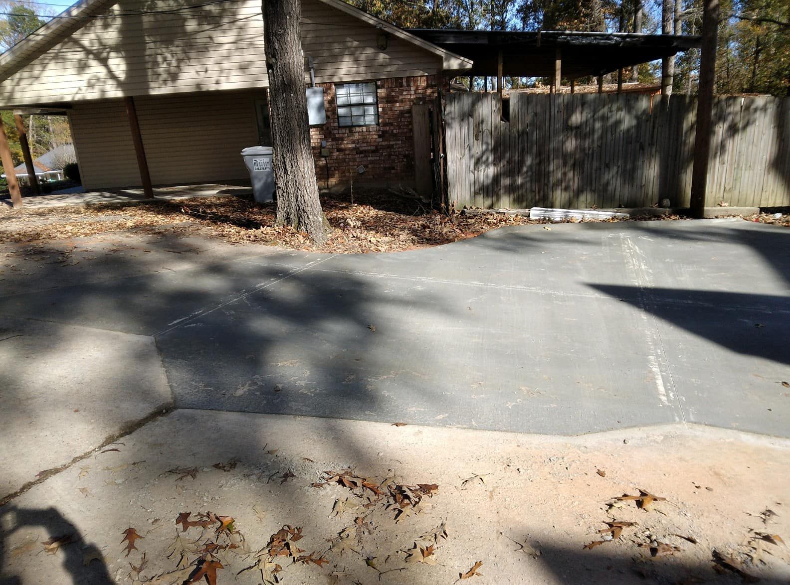 A house with a fence and a driveway in front of it.